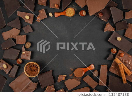Chocolate pieces, nuts, cocoa powder and spices arranged around empty dark background with ample copy space for dessert menus, branding or advertising Chocolate pieces, nuts, cocoa powder and spices arranged around empty dark background with ample copy space for dessert menus, branding or advertising 133487188