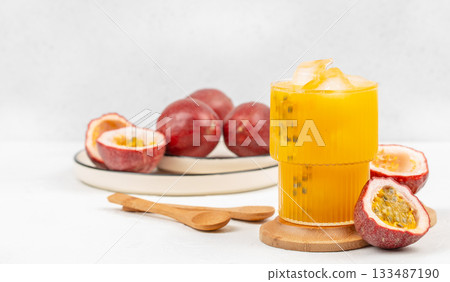 Fresh passion fruit juice in a glass with ice and ripe passion fruits on a white background 133487190