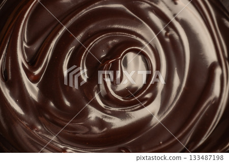 Rich melted chocolate swirl close-up with glossy texture and decadent dessert background. Rich melted chocolate swirl close-up with glossy texture and decadent dessert background. 133487198