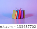 Colorful paper shopping bags on neon background. Creative idea for shopping online, summer sale, supermarket, discount promotion and Black Friday concept. 133487702