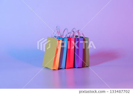 Colorful paper shopping bags on neon background. Creative idea for shopping online, summer sale, supermarket, discount promotion and Black Friday concept. 133487702