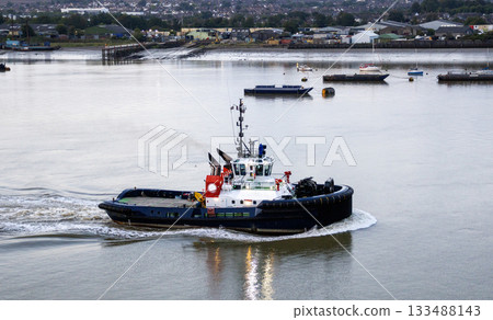 Tugboat Navigating the Calm Waters Near the Harbor at Sunrise 133488143