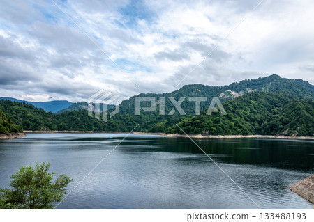 Majestic summer lake, Okutadami Lake, Niigata Prefecture, cloudy sky and deep green mountain range 133488193