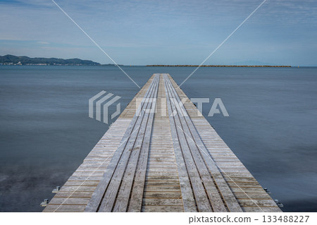 The sea at Nago Pier in Chiba Prefecture, a long pier leading to a sandy beach and the blue autumn sky 133488227