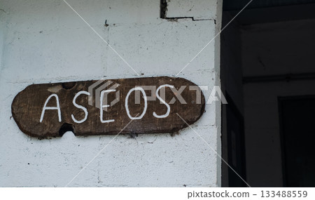 Rustic wooden sign with the Spanish word ASEOS handwritten in white paint, meaning toilets or restrooms Rustic wooden sign with the Spanish word ASEOS handwritten in white paint, meaning toilets or restrooms 133488559