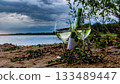 Wine Glasses and Bottle on Sandy Lakeshore at Sunset 133489447