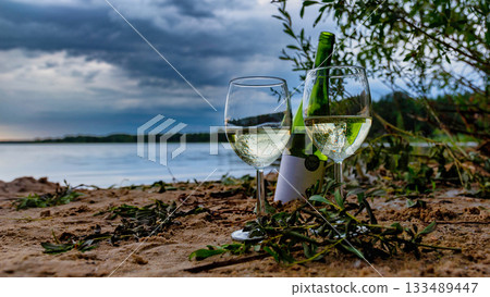 Wine Glasses and Bottle on Sandy Lakeshore at Sunset 133489447