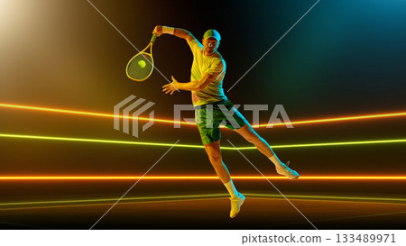 Jumping tennis player performing backhand in mid-air illuminated by colored lights. Handmade collage Jumping tennis player performing backhand in mid-air illuminated by colored lights. Handmade collage 133489971