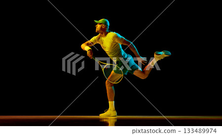 Tennis player stretching to hit low ball under neon light with focus 133489974