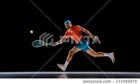 Male tennis player running to reach fast ball during match moment Male tennis player running to reach fast ball during match moment 133489979