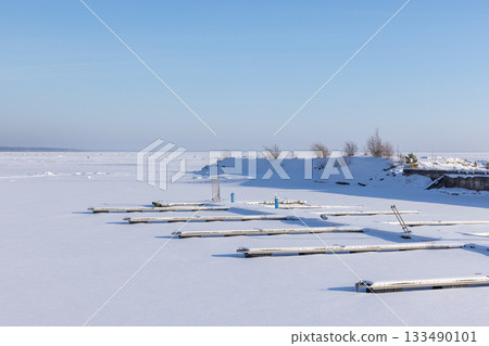A serene winter seaside scene shows snow-covered docks 133490101