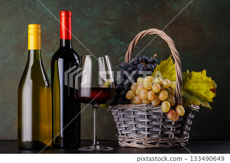 Red and white wine bottles with a glass and basket of fresh grapes Red and white wine bottles with a glass and basket of fresh grapes 133490649