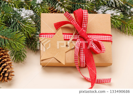 Gift box on snowy fir branches and beige background 133490686