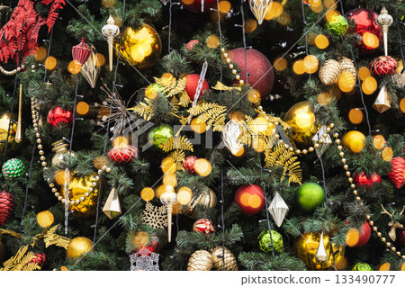 Details decorated Christmas tree with red, golden baubles and garland. Xmas card and pattern. Close up. Winter. Outdoor. Details decorated Christmas tree with red, golden baubles and garland. Xmas card and pattern. Close up. Winter. Outdoor. 133490777