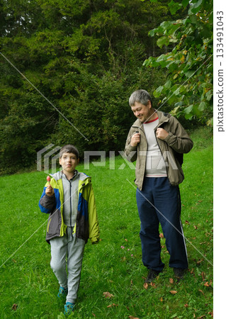 Dad and son walking in the summer forest. Dad and son walking in the summer forest. 133491043