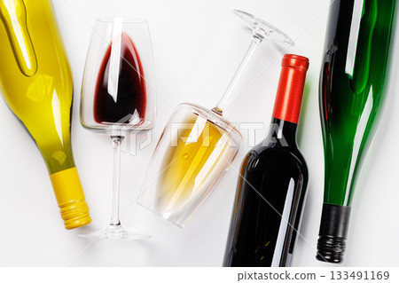 Wine glasses with red and white wine and bottles lying on white background Wine glasses with red and white wine and bottles lying on white background 133491169