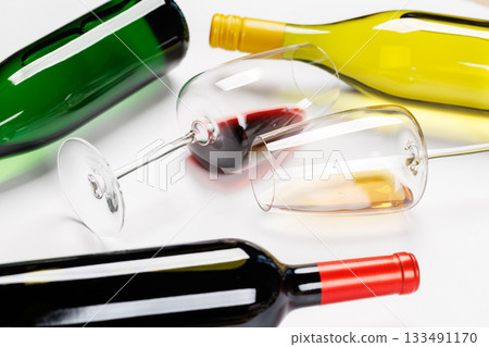 Wine glasses with red and white wine and bottles lying on white background Wine glasses with red and white wine and bottles lying on white background 133491170