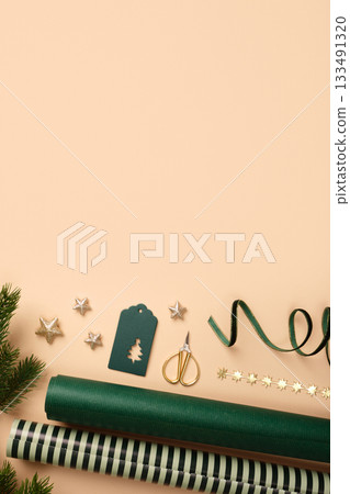 Christmas wrapping paper rolls, green gift tag, and gold stars on beige background. Copy space for holiday text or design. 133491320