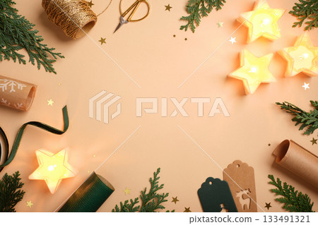 Christmas frame with star candles, fir branches, gift tags, and wrapping supplies on beige background. Copy space for text or design. Christmas frame with star candles, fir branches, gift tags, and wrapping supplies on beige background. Copy space for text or design. 133491321