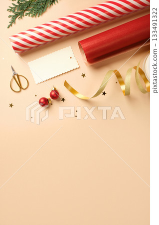 Christmas gift wrapping with red and white striped wrapping paper, ribbon, baubles, scissors, cedar spruce on beige backdrop. Copy space. Christmas gift wrapping with red and white striped wrapping paper, ribbon, baubles, scissors, cedar spruce on beige backdrop. Copy space. 133491322