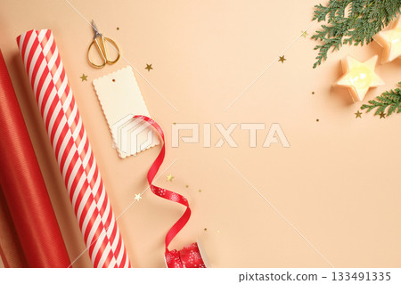 Christmas gift wrapping with red and white striped wrapping paper, ribbon, scissors, thuja spruce, candles on beige backdrop. Copy space. Christmas gift wrapping with red and white striped wrapping paper, ribbon, scissors, thuja spruce, candles on beige backdrop. Copy space. 133491335