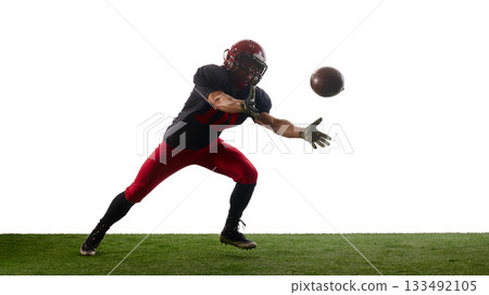 Football player reaching for airborne ball with urgent emotional drive 133492105
