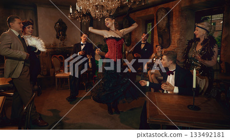 Glamorous retro dancer in red corset performing for stylish friends in vintage club Glamorous retro dancer in red corset performing for stylish friends in vintage club 133492181