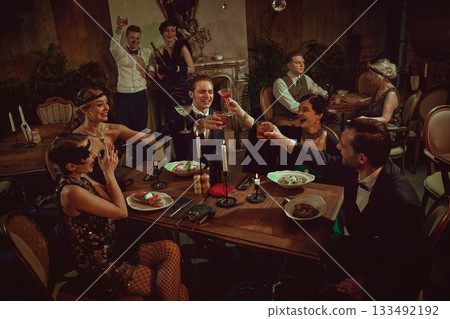 Stylish retro friends celebrating and toasting at festive dinner table setting Stylish retro friends celebrating and toasting at festive dinner table setting 133492192