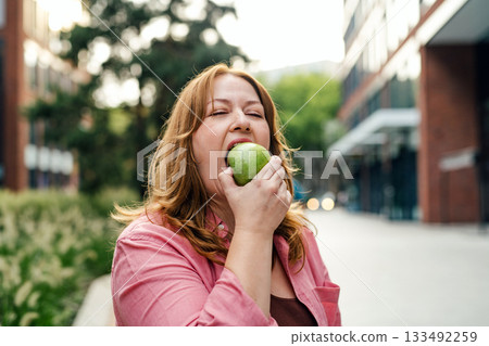 Plus size woman holding green apple. Plus size woman holding green apple. 133492259
