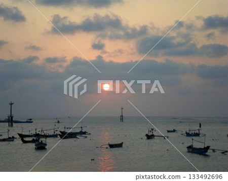 Peaceful Sunset Over the Ocean with Scattered Boats Reflecting the Sun's Glow 133492696
