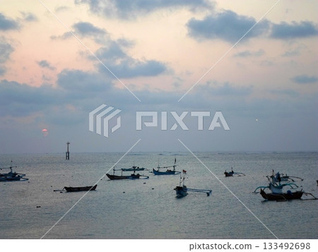 Gentle Sunset Over the Ocean with Boats and a Platform Under a Cloudy Sky Gentle Sunset Over the Ocean with Boats and a Platform Under a Cloudy Sky 133492698