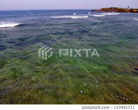 Crystal Clear Ocean Waters with Distant Waves and a Coastal Headland on a Bright Day 133492721