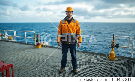 Offshore Worker in Safety Gear on Platform Overlooking Vast Sea 133492811