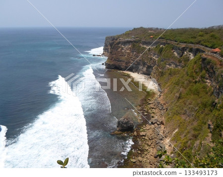 A Cliffside View of a Beach with Waves Crashing Against Rocks and a Pathway Along the Edge A Cliffside View of a Beach with Waves Crashing Against Rocks and a Pathway Along the Edge 133493173