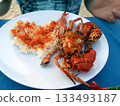A Plate of Grilled Seafood with Rice and Spicy Sauce on a Beachside Dining Table 133493187