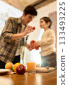 Fresh orange juice in glass with blurred father and son fruit prep in warm kitchen 133493225