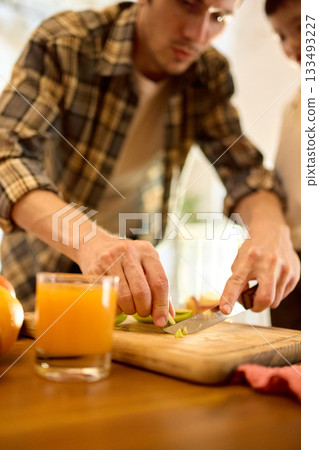 Fresh orange juice in glass on wooden table with warm father and son cooking mood 133493227