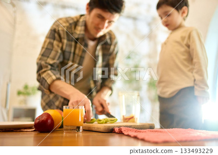 Glass of orange juice with bright kitchen daylight and warm caring family vibe Glass of orange juice with bright kitchen daylight and warm caring family vibe 133493229