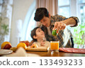 Orange juice glass with soft natural light and cheerful family kitchen atmosphere 133493233