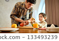 Glass of orange juice on wooden table with bright cozy mood and soft family interaction 133493239