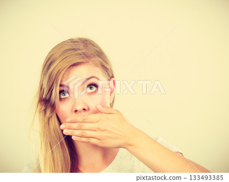 Ashamed woman having hand on mouth 133493385