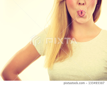 Funny blonde woman sitcking tongue out Funny blonde woman sitcking tongue out 133493387