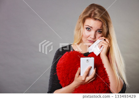 Sad heartbroken woman looking at her phone 133493429