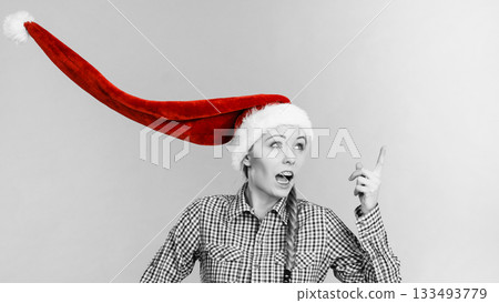 Surprised girl wearing blowing santa claus hat Surprised girl wearing blowing santa claus hat 133493779