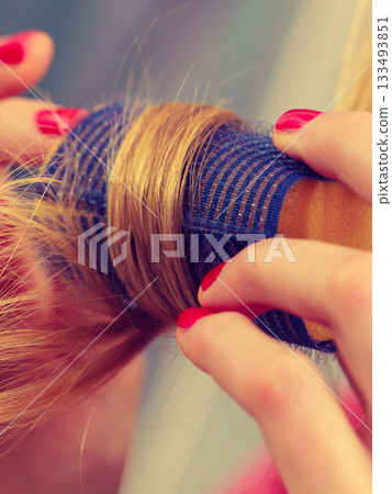 Woman curling her hair using rollers Woman curling her hair using rollers 133493851