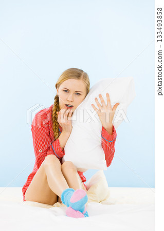 Young woman wearing pajamas hugging soft pillow 133493858
