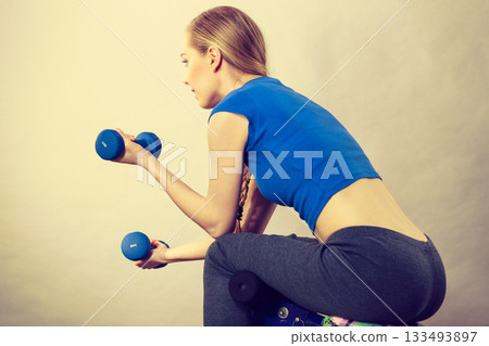 Teenage woman working out at home with dumbbell Teenage woman working out at home with dumbbell 133493897