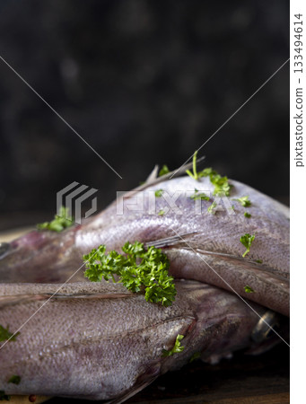 Fresh European hake fish on wooden board, Raw uncooked Merluccius merluccius close-up, copy space 133494614