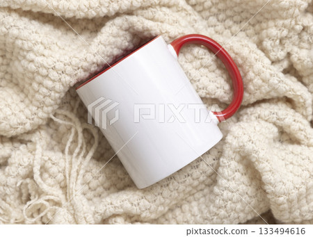 White accented coffee mug with red handle on beige plaid top view, boho mockup 133494616