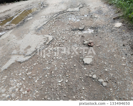 damage poor road and rain water. cracked old asphalt in need of repair. The road is full of holes and potholes. damage poor road and rain water. cracked old asphalt in need of repair. The road is full of holes and potholes. 133494650